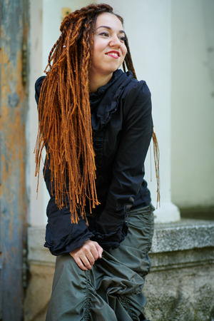 dreadlocks fashionable girl posing at old wooden door backgroundの写真素材