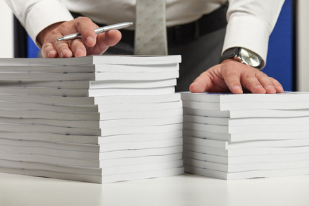 Businessman working at an office, reads stack of books and reports. Business financial accounting...