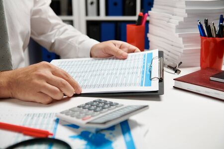 Businessman working and calculating, reads and writes reports. Office employee, table closeup. Business financial accounting concept.の写真素材