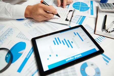 Businessman working and calculating, reads and writes reports. Using tablet pc. Office employee,...