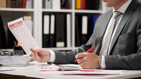Businessman working and calculating, reads and writes reports. Office employee, table closeup....