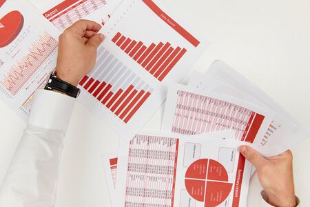 Business reports, data tables and charts - directly above view of office table workspace.