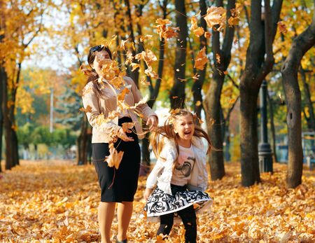 Happy family having holiday in autumn city park. Children and parents posing, smiling, playing and having fun. Bright yellow trees and leavesの写真素材