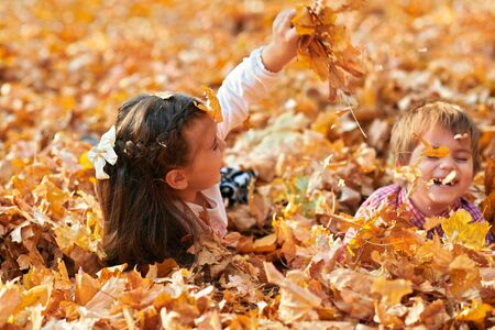 Happy children playing, posing, smiling and having fun in autumn city park. Bright yellow trees and leavesの写真素材