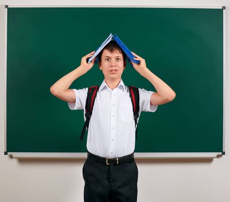 Portrait of a school boy posing with backpack and school supplies, blackboard background - back to school and education conceptの写真素材