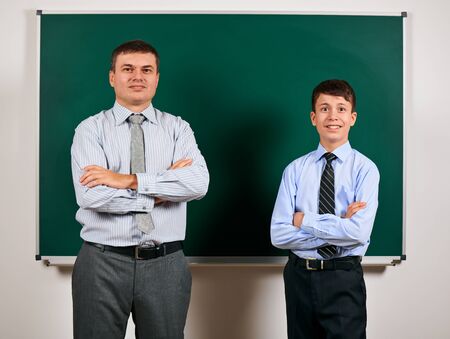 Portrait of a man and boy dressed in a business suits near blackboard background - learning and education conceptの写真素材