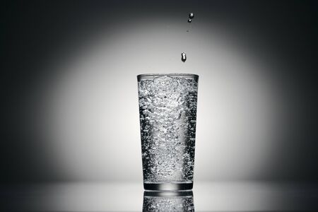 one glass of sparkling water on a dark background