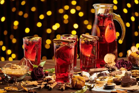 Christmas mulled wine or gluhwein with spices, chocolate sweets and orange slices on rustic table, traditional drink on winter holiday, christmas lights and decorationsの写真素材