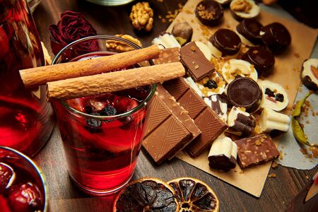 Christmas mulled wine or gluhwein with spices, chocolate candies, sweets and orange slices on rustic table, traditional drink on winter holiday, christmas lights and decorationsの写真素材