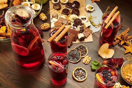 Christmas mulled wine or gluhwein with spices, chocolate candies, sweets and orange slices on rustic table, traditional drink on winter holiday, christmas lights and decorationsの写真素材