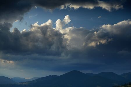 Sunset in carpathian mountains - beautiful summer landscape, spruces on hills, dark cloudy sky and...