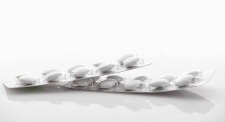 White tablets in blister package on white background. Global healthcare concept. Antibiotics drug...