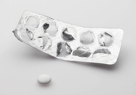 Empty, used, opened blister with last one white pill on white background - healthcare and medicament concept. Pharmaceutical industry. Pharmacy.の写真素材