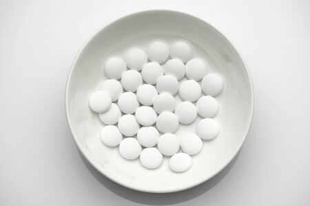 Group of white pills in a plate on white background - healthcare and medicament concept. Pharmaceutical industry. Pharmacy.の写真素材