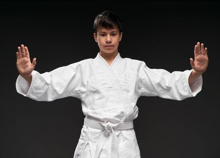 portrait of a teenager dressed in martial arts clothing poses on a dark gray background, a sports conceptの写真素材