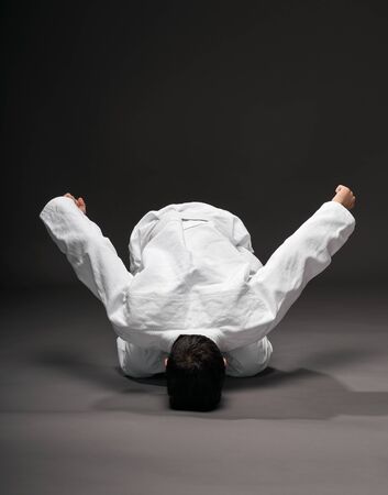 sport concept - greeting bow, a teenager dressed in martial arts clothing poses on a dark gray background, studio shootの写真素材