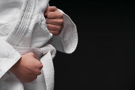 hands closeup - teenager dressed in martial arts clothing posing on a dark gray background, a sports conceptの写真素材