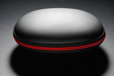 black hard bag in a shell form with red zipper on dark background