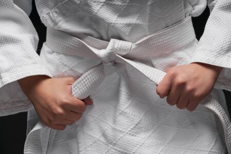 hands closeup - teenager dressed in martial arts clothing posing on a dark gray background, a sports conceptの写真素材