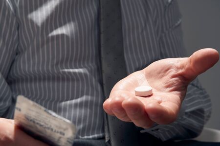 businessman with a pill, hands close view - concept of difficulties, depression, problems, health and stress, risk of modern businessの写真素材