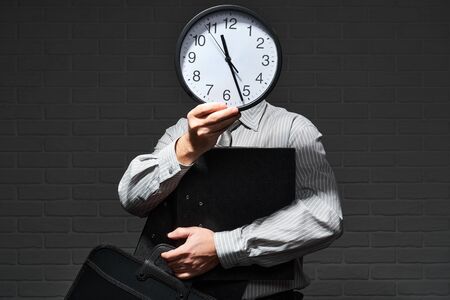 Businessman closeup portrait, he stands and shows the clock in front of his head, time and schedule...