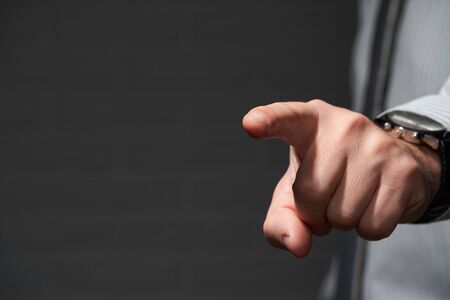 Businessman standing and pointing with his finger, hand closeup.