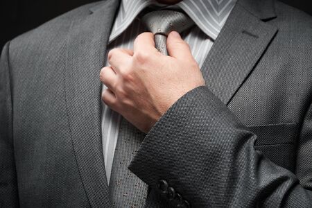 businessman portrait dressed in gray suit, dark wall backgroundの写真素材