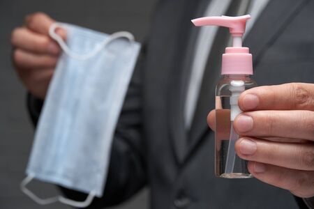 a man demonstrates a protective face mask for antivirus individual protection and bottle of...