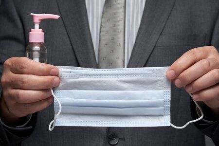 a man demonstrates a protective face mask for antivirus individual protection and bottle of sanitizer liquid- healthcare and medicine concept, prevention tipsの写真素材