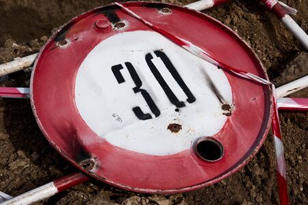 the road sign for the speed limit of thirty kilometers or miles per hour and the road fence for performing repair work lies on the groundの写真素材