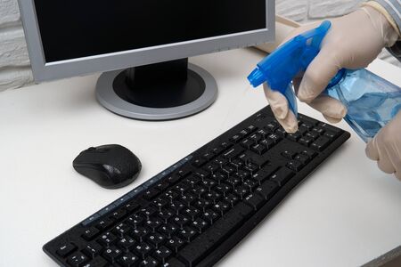 concept of cleaning or disinfecting the office - a businessman cleans the workplace, computer, desk,...