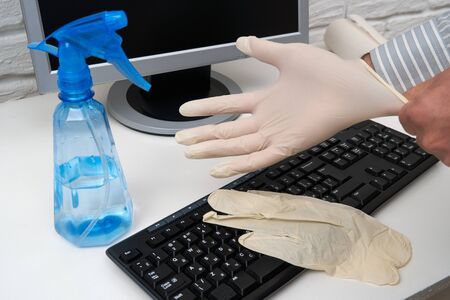 concept of cleaning or disinfecting the office - a businessman cleans the workplace, computer, desk,...
