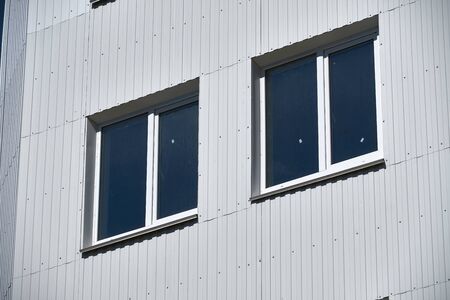 facade of a new multistory building with white and green metal siding, many Windows