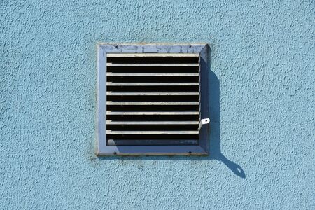 square metal ventilation grate in a blue wall, close view, delivers fresh air and cools