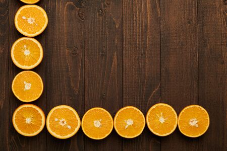 dark wooden background with blank space for text and fresh sliced orange fruits as a corner - natural and healthy food.の写真素材