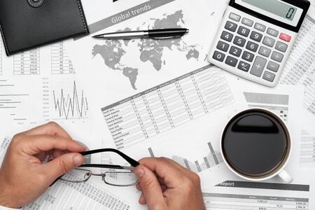 Top view of businessman working with financial statements. Modern black office desk with notebook,...