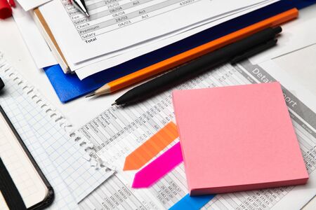 Top view of office worker's desk - work with financial reports, analysis and accounting, tables and graphs, various office items for bookkeepingの写真素材