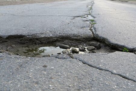 crack in the asphalt of the road and a puddleの写真素材