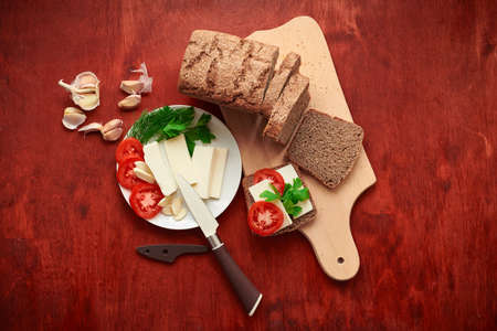 healthy food - fresh bread and feta cheese on a wooden background, tomatoes, greens and vegetables