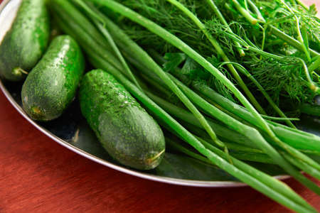 healthy food - fresh vegetables and greens on a wooden background, greens, onion and cucumbersの写真素材