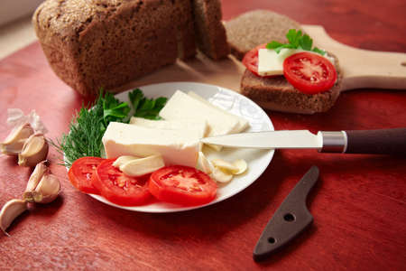healthy food - fresh bread and feta cheese on a wooden background, tomatoes, greens and vegetablesの写真素材