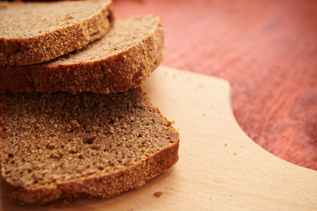 healthy food - fresh sliced bread on a cutting board, wooden background