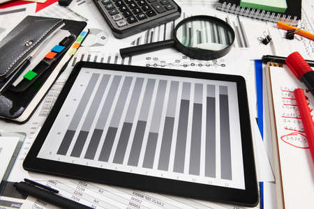 Top view of office employee's desk - work with tablet pc computer and financial reports, analysis...
