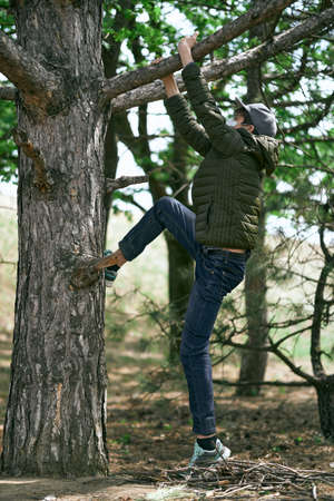 teenage boy poses on a tree, wearing a protective face mask - the concept of modern life and virus protectionの写真素材