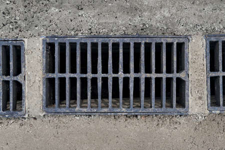 New rainwater grate on the road or sidewalk, installation in concrete. City sewage system for...