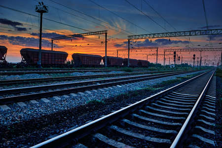 railway and rail cars in a beautiful sunset, dramatic sky and sunlightの写真素材