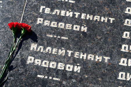 Russian language phrase "sergeant,major, colonel,lieutenant, ranker" - army ranks, flowers on the memorial to fallen soldiers, red carnations on black marbleのeditorial素材