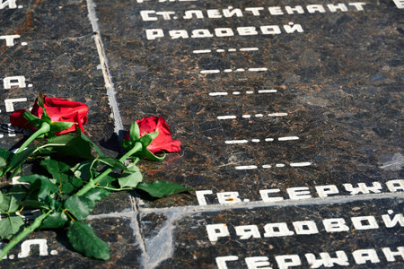 Russian language phrase "sergeant,major, colonel,lieutenant, ranker" - army ranks, flowers on the memorial to fallen soldiers, red carnations on black marbleのeditorial素材