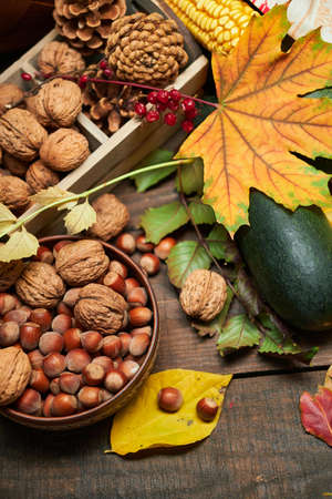 autumn still life in rustic style as a background - leaves, vegetables and fruits, nuts and other natural food ingredients on wooden boardsの写真素材