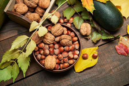 autumn still life in rustic style as a background - leaves, vegetables and fruits, nuts and other natural food ingredients on wooden boardsの写真素材